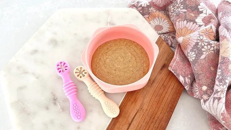 Caramel Apple Oats in pink silicone suction plate with sticky spoons on chopping board - Starting Solids Australia recipe.