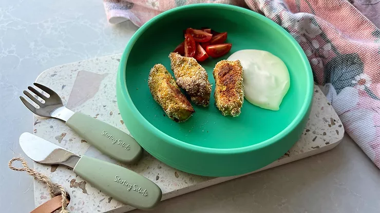 Chicken Nuggies with dipping sauce and chopped cherry tomatoes on a terrazzo board with toddler cutlery - Starting Solids Australia recipe.