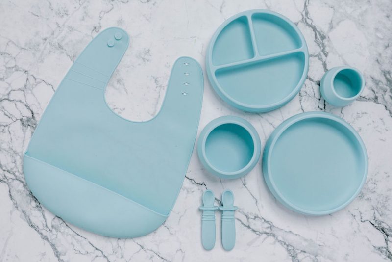 Blue silicone bib, Bubbie Cup, Suckie Scoop Divided Plate, Suckie Scoop Plate, Suckie Scoop Bowl and Selfie Spoon set for babies by Starting Solids Australia, on a marble bench.