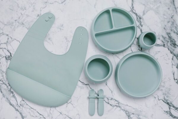 Grey silicone bib, Bubbie Cup, Suckie Scoop Divided Plate, Suckie Scoop Plate, Suckie Scoop Bowl and Selfie Spoon set for babies by Starting Solids Australia, on a marble bench.