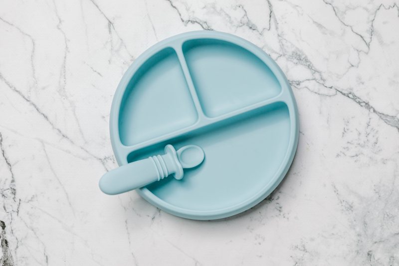 Blue Suckie Scoop Divided Plate with Selfie Spoon by Starting Solids Australia, on a marble bench.