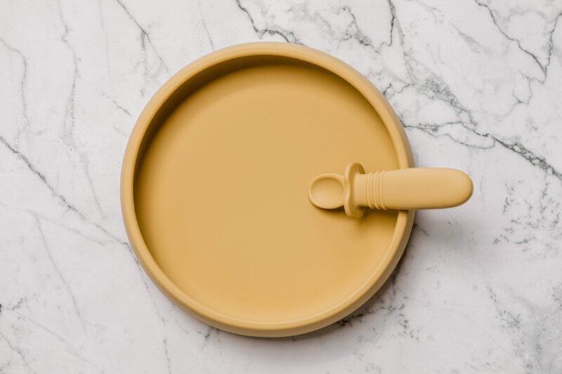 Yellow Suckie Scoop Plate with Selfie Spoon by Starting Solids Australia, on a marble bench.