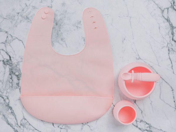 Pink (Fairy Floss) silicone bib, cup, bowl and spoon set for babies on a marble bench by Starting Solids Australia