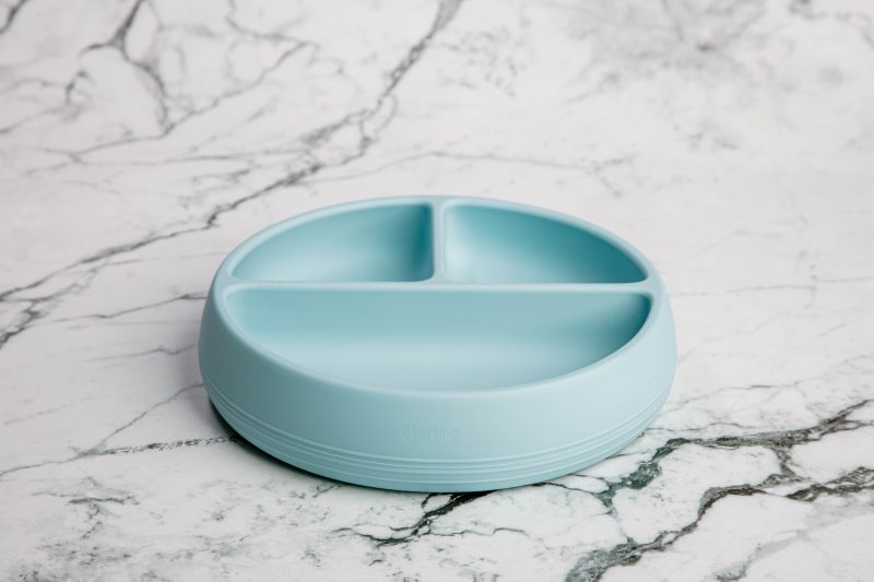 Suckie Scoop Divided Plate in 'Blue Lemonade' by Starting Solids Australia on a marble bench.