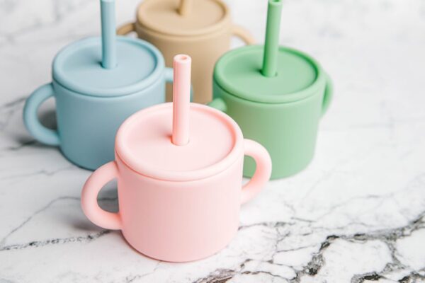 Four different coloured Ideal First Baby Cups by Starting Solids Australia on a marble bench