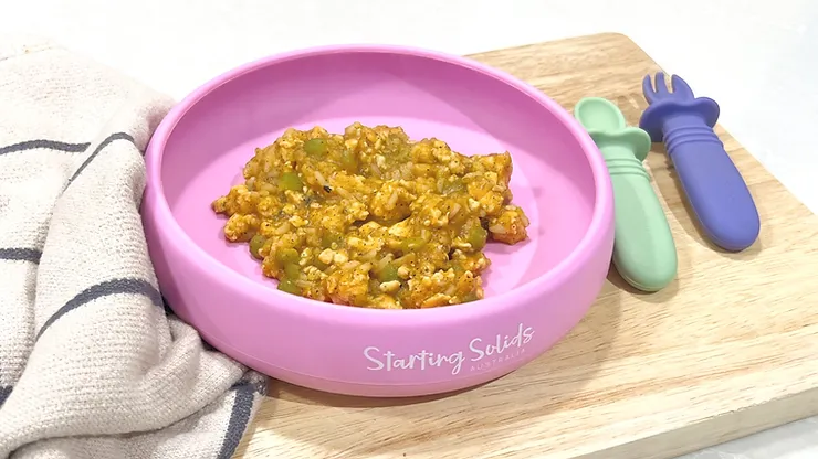 Sweet Chicken and lentils in silicone suction plate with baby cutlery on a wooden board - Starting Solids Australia recipe.