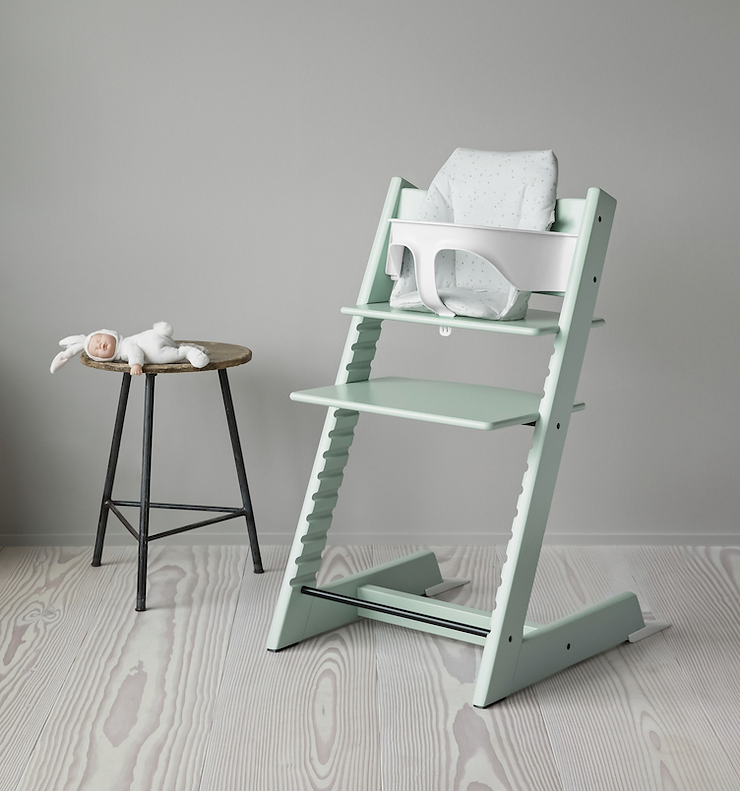 Pastel green Tripp Trap highchair and stool with bunny toy on it.