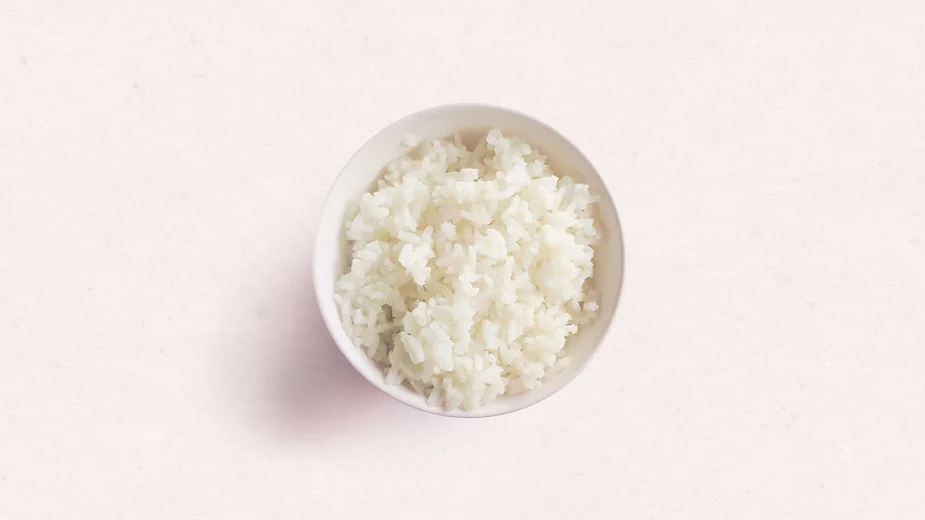 Birdseye view of a small bowl of white rice on a neutral background