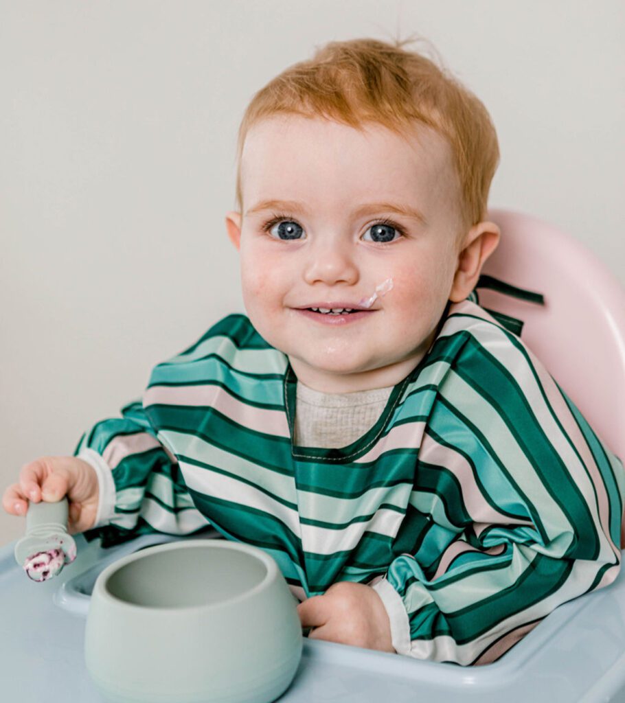 Baby eating puree with Starting Solids Australia feeding ware in a high chair.