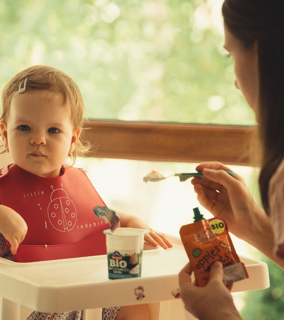 Baby bring fed yoghurt by mum