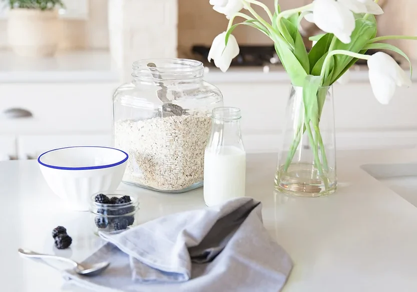 Ingredients for porridge on a bench with a vase of white tulips.