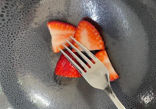 Chopped strawberries in a grey bowl with a fork