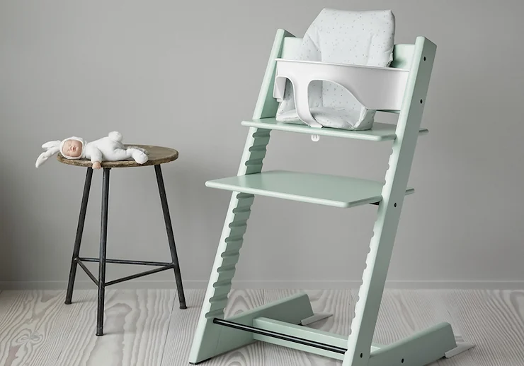 Pastel green Tripp Trap highchair and stool with bunny toy on it.