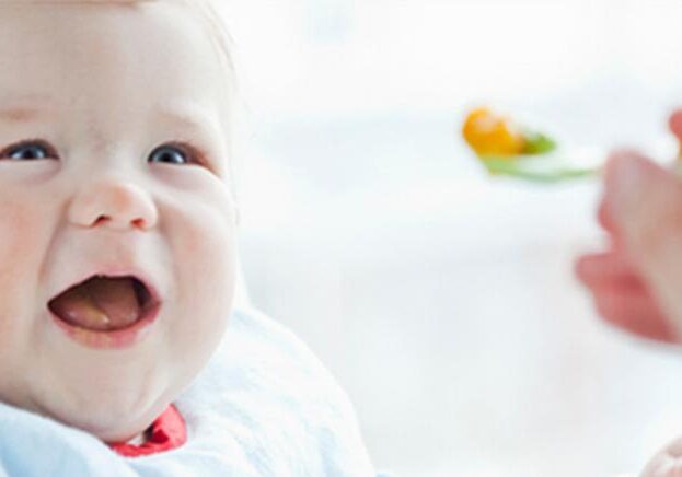 Baby being spoon fed solid foods.