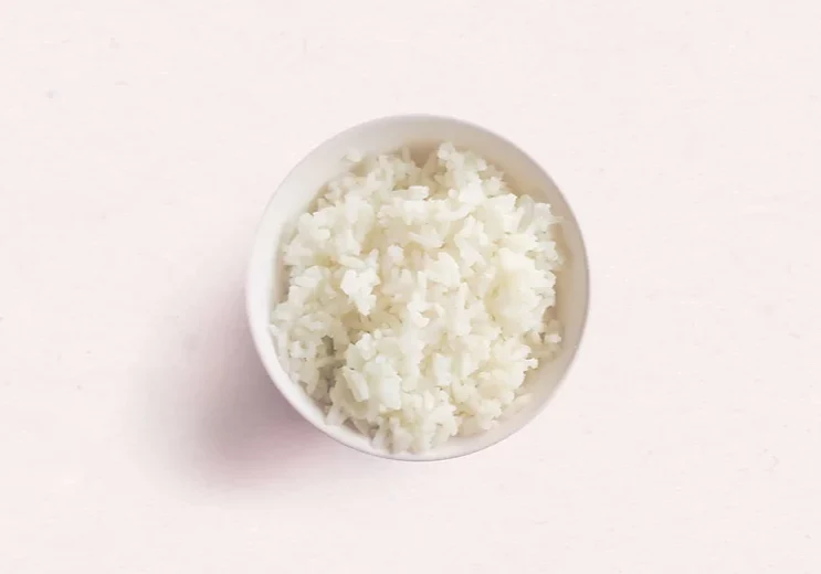 Birdseye view of a small bowl of white rice on a neutral background